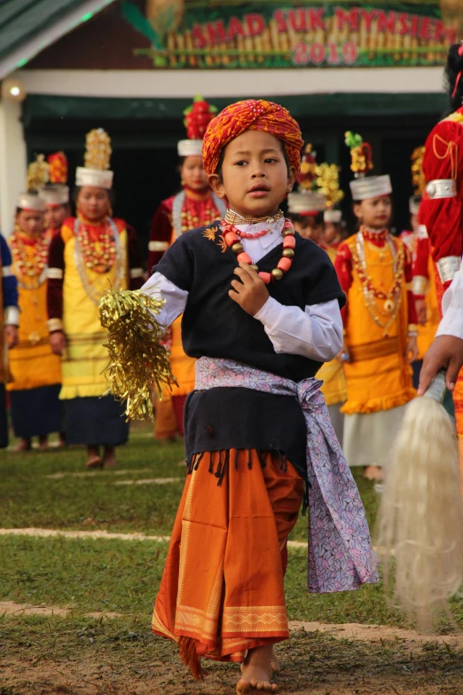 a little boy with orange skirts standing next to a couple of men in orange and blue costumes