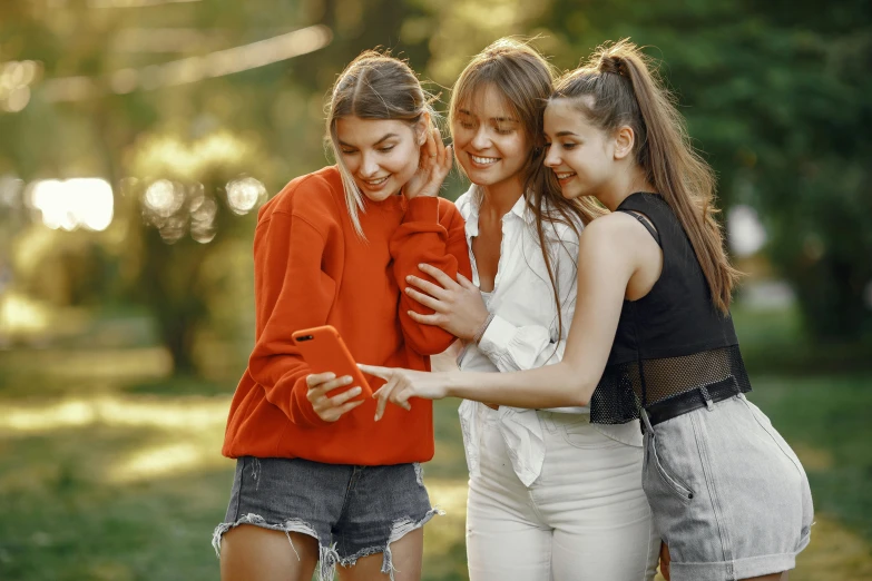 four girls laugh and emce outside in the park