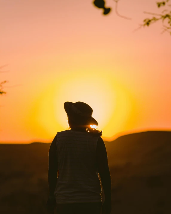 a woman standing in a field watching the sun rise