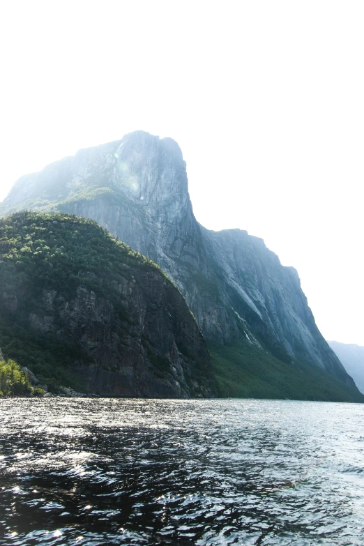 a boat is traveling across the water with a large mountain in the distance