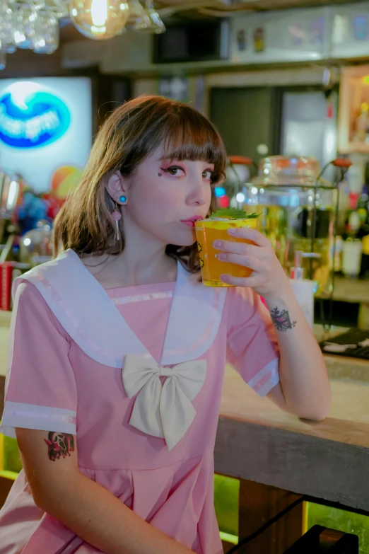 woman in pink dress sitting at a counter drinking from a drink