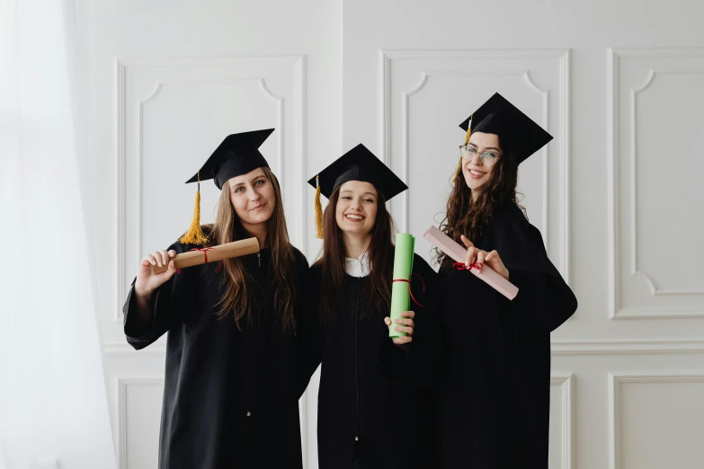 three girls in caps and gowns are dressed as graduates with diplomas