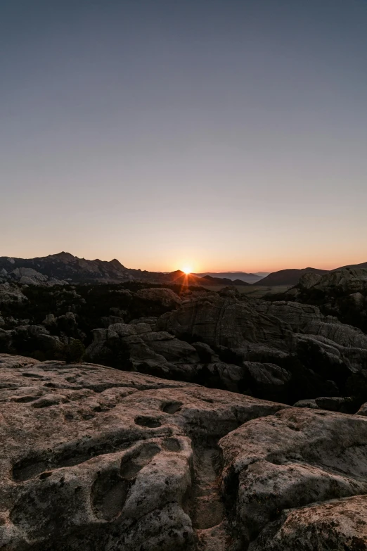 the sun is setting over some large rocks