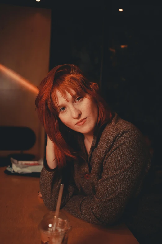 a  sitting at a table with a cigarette in her hand