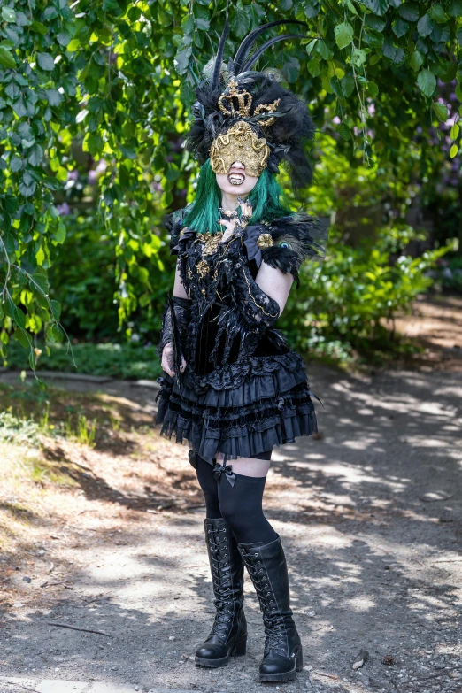 a woman with green hair in a costume standing under a leaf covered tree