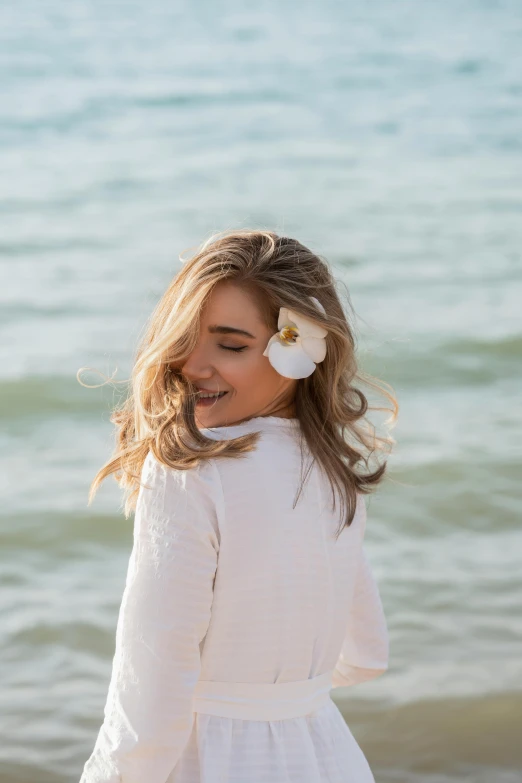 a girl is standing by the water wearing a flower in her hair