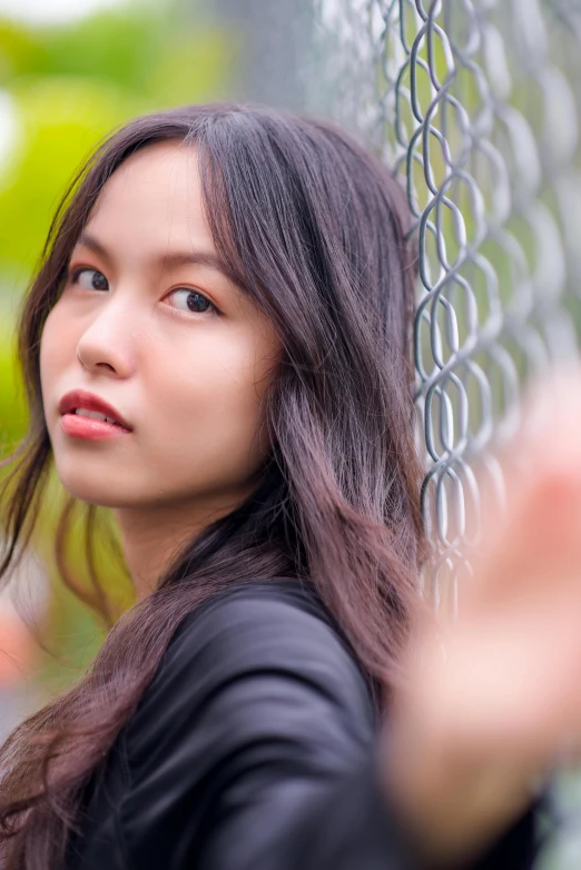 an asian girl standing by a chain link fence