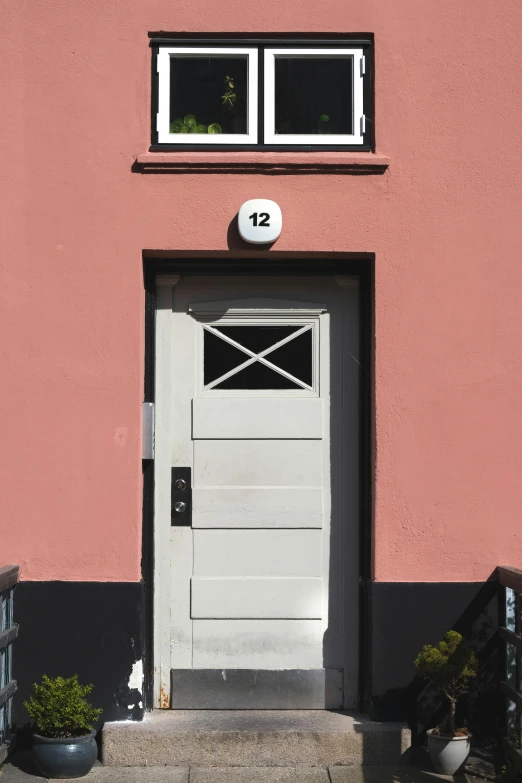 a gray door is in front of a pink building