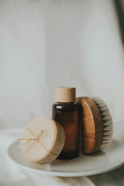 a small wooden brush and round hair comb sitting on top of a white plate