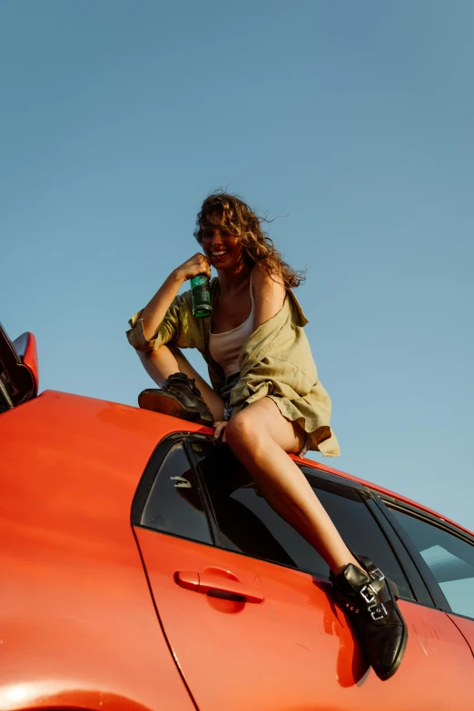 a person sitting on the roof of an orange car