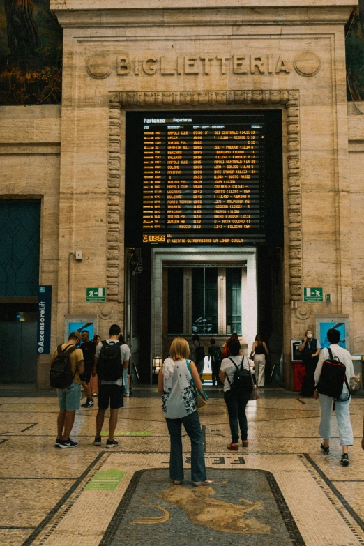 people are walking through a station with the information sign