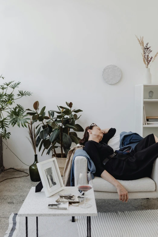 a person on a sofa with plants and plants behind