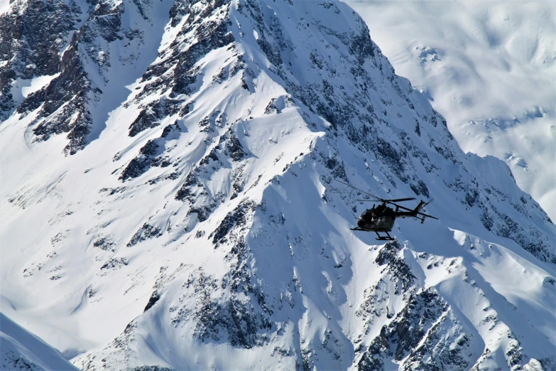 a helicopter flying in the air near snow covered mountains