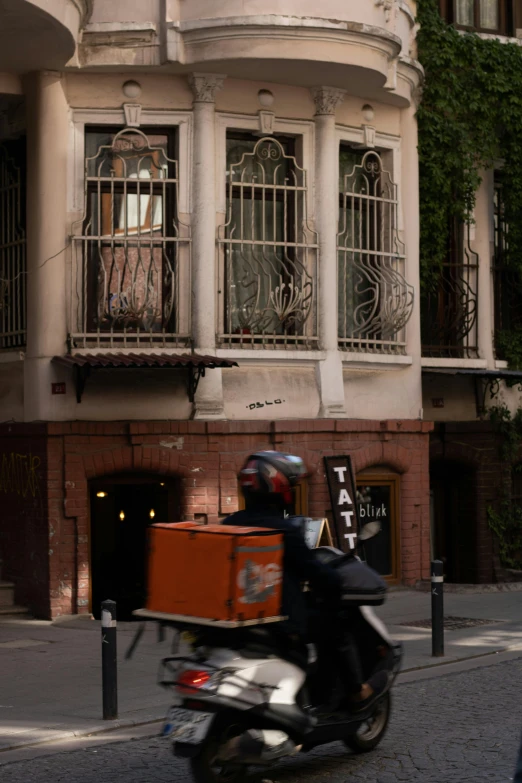 a man on a motorcycle with a suitcase in front of an apartment building