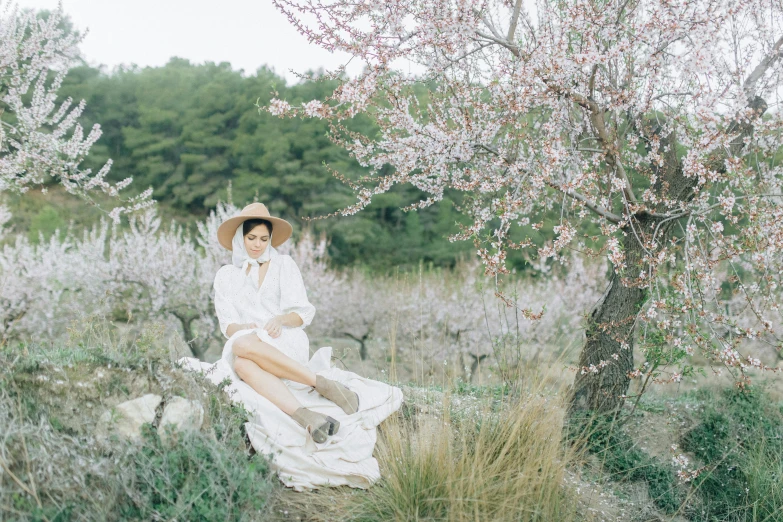 two women sitting in the middle of a field near trees