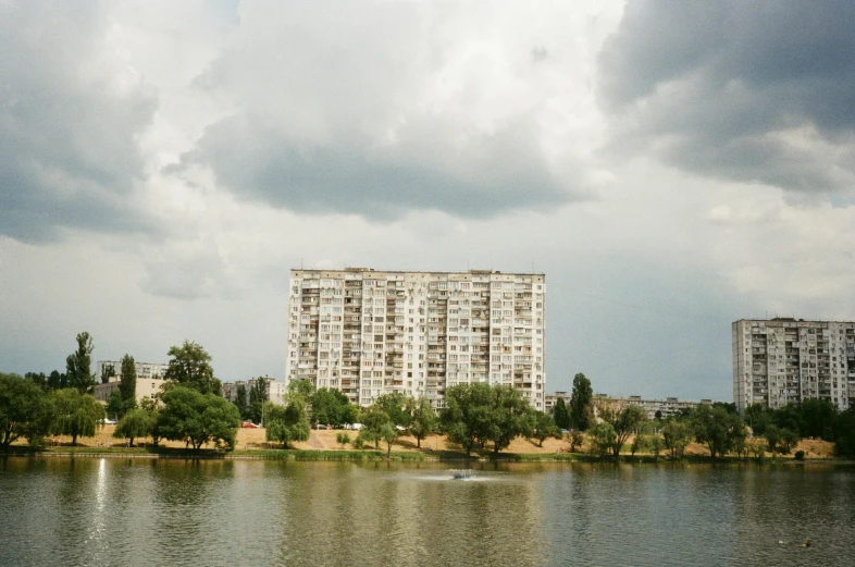 a large building stands on a cloudy day above a lake