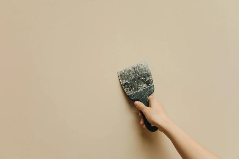 a hand holding up a sponge to paint wall with white and beige accents