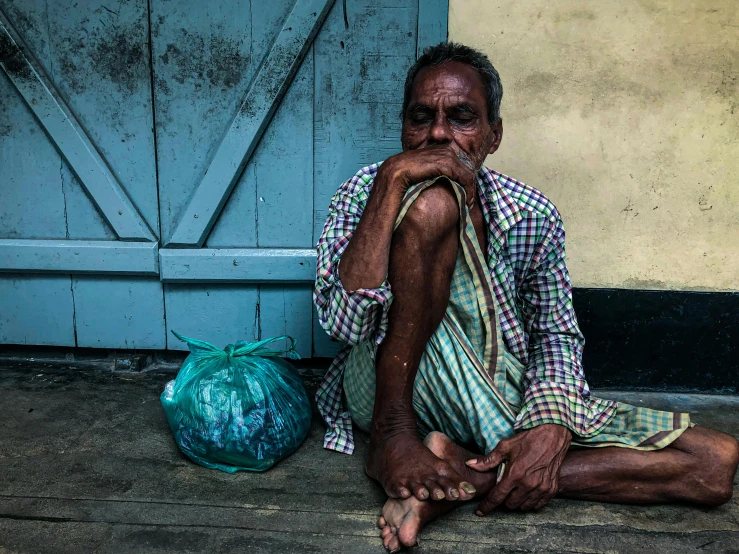 an old man sits with his foot on the ground