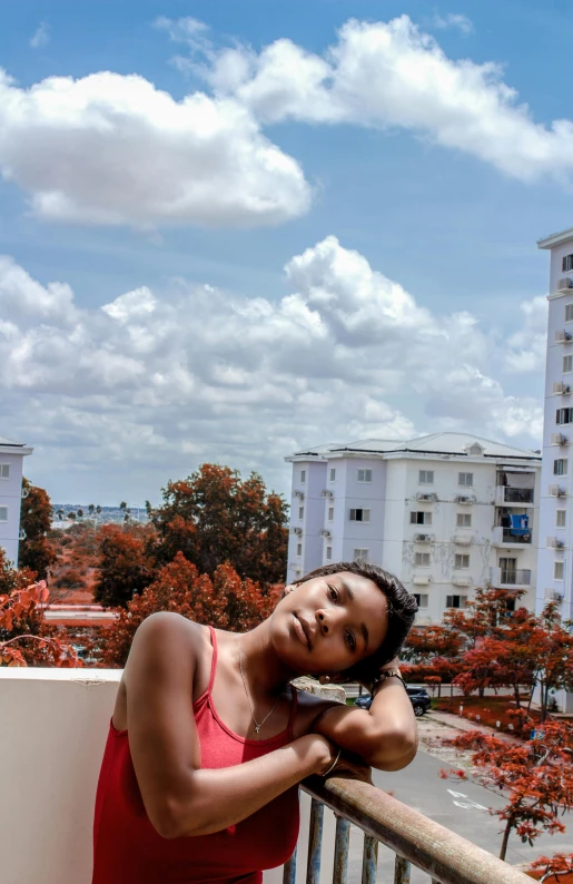 a woman wearing a red dress leaning on a balcony