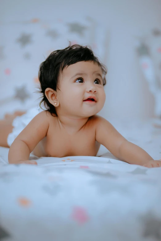 small baby laying on a bed looking up