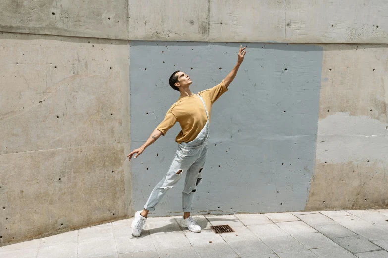 a young man stands on concrete while holding his arms up in the air