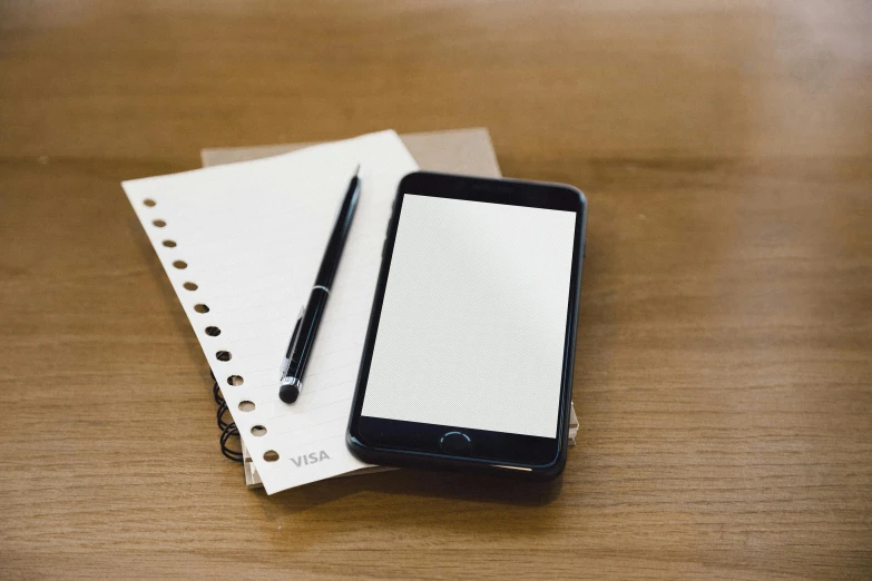 a note pad and smartphone sitting on a desk