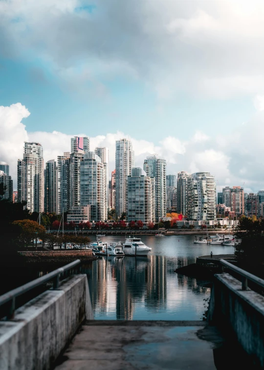 city skyline with boats in a harbor and cloudy sky