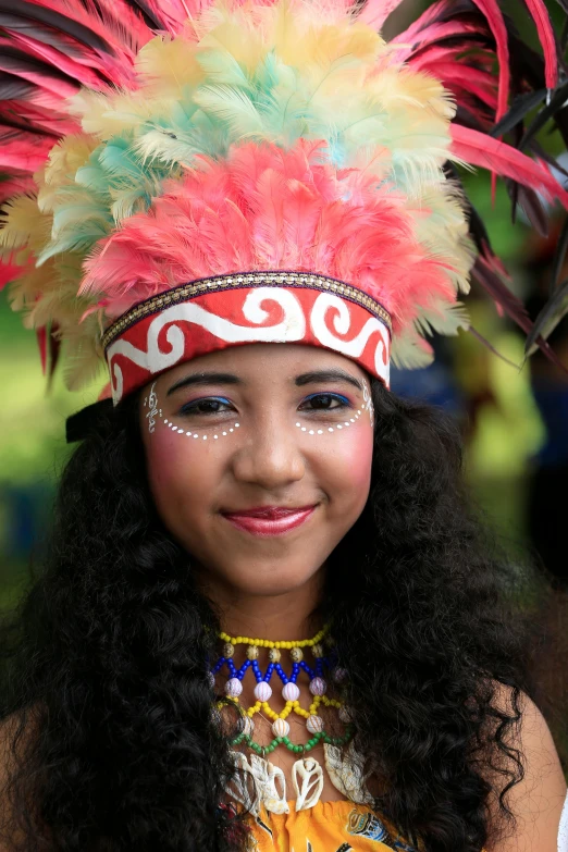 girl with long dark hair and bright makeup wearing headdress and feathers