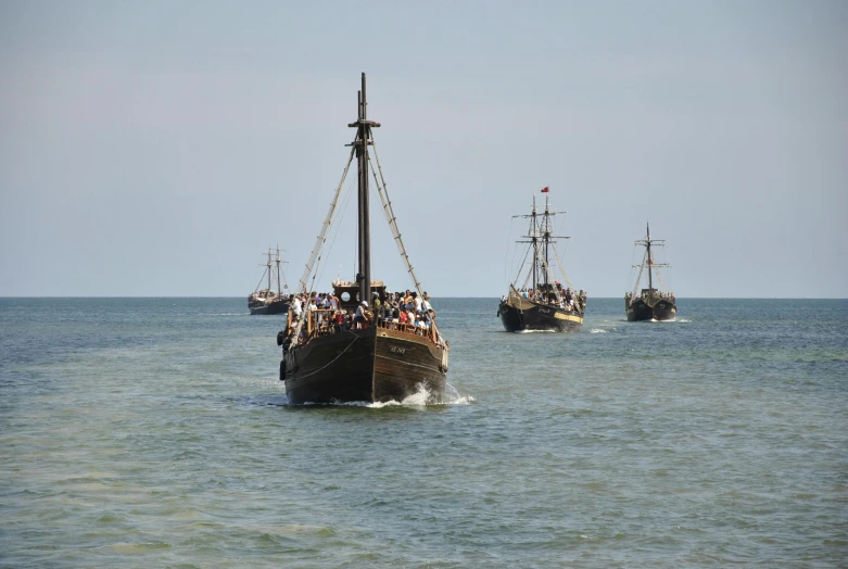 two boats sailing in the ocean with people on them