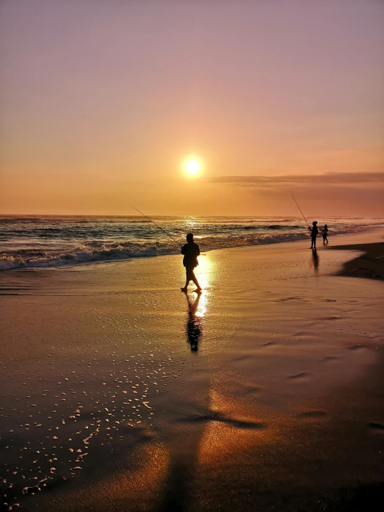 silhouettes of two people on the beach at sunset