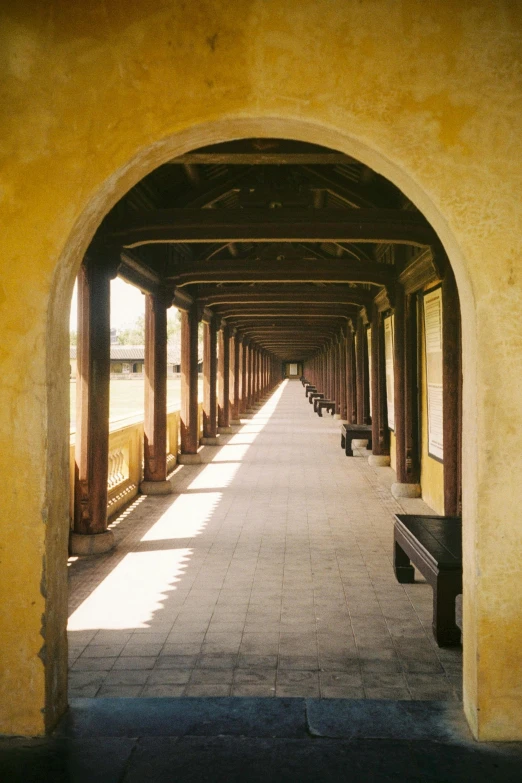 a yellow wall is lining a road lined with benches