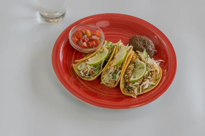 an orange plate with some tacos on it and a glass of water