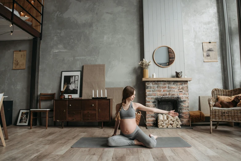 woman in yoga attire seated in front of a brick fireplace