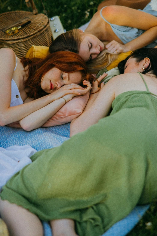 three people laying next to each other on a blanket