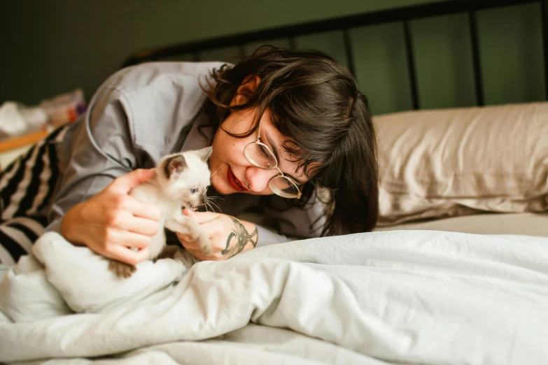 a woman smiling and petting a puppy in bed