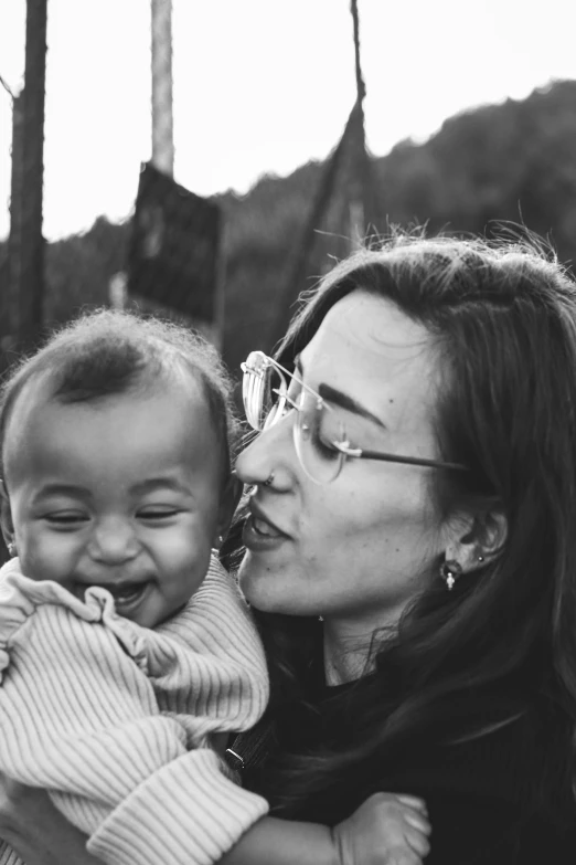 two woman are holding a baby on a field