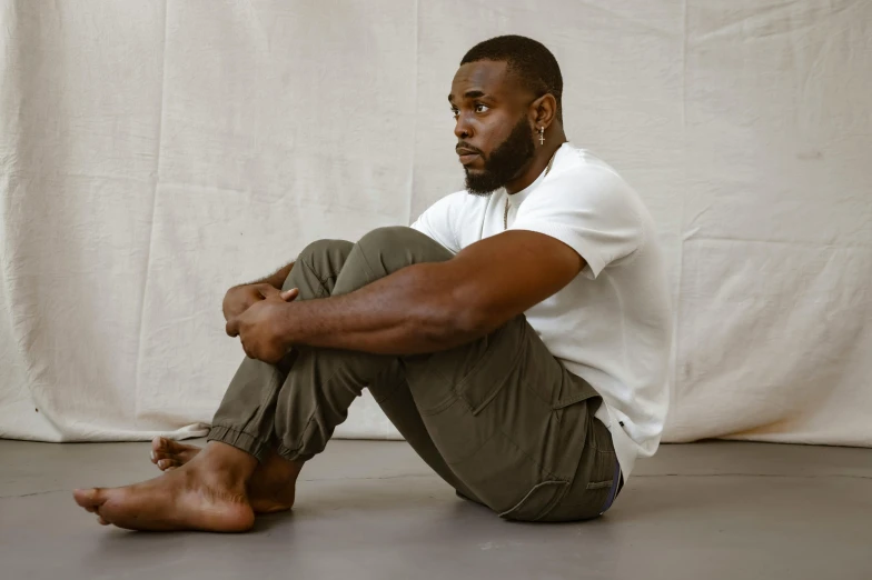 a man sitting in front of a white curtain