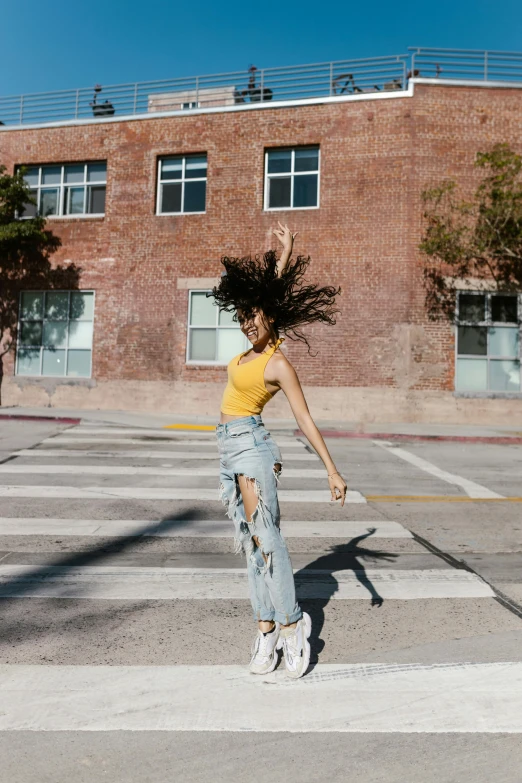 a girl doing a trick on a skateboard across the street from a brick building