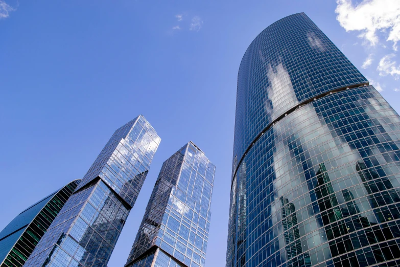 a group of three skyscrs towering up into the blue sky