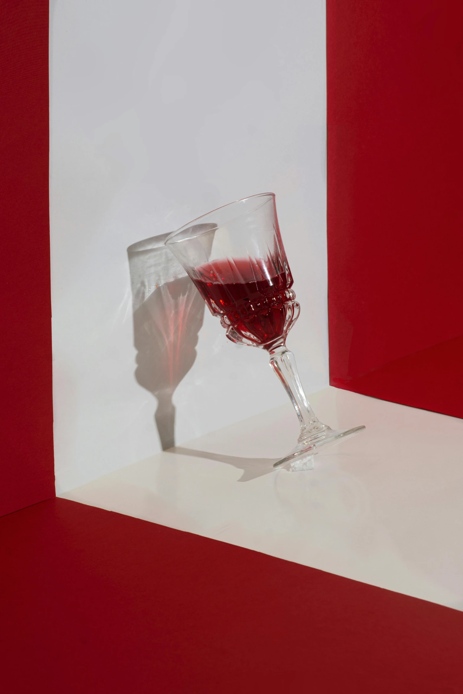 a single glass of red wine is casting a shadow on the counter