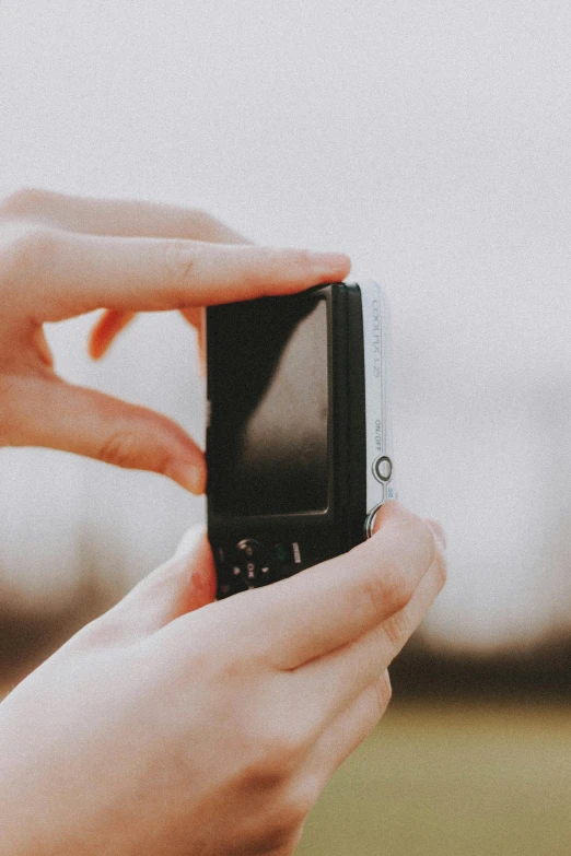 someone holding a black cell phone with the top of it