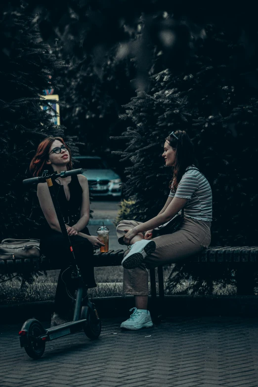 two people sitting on a bench near a park