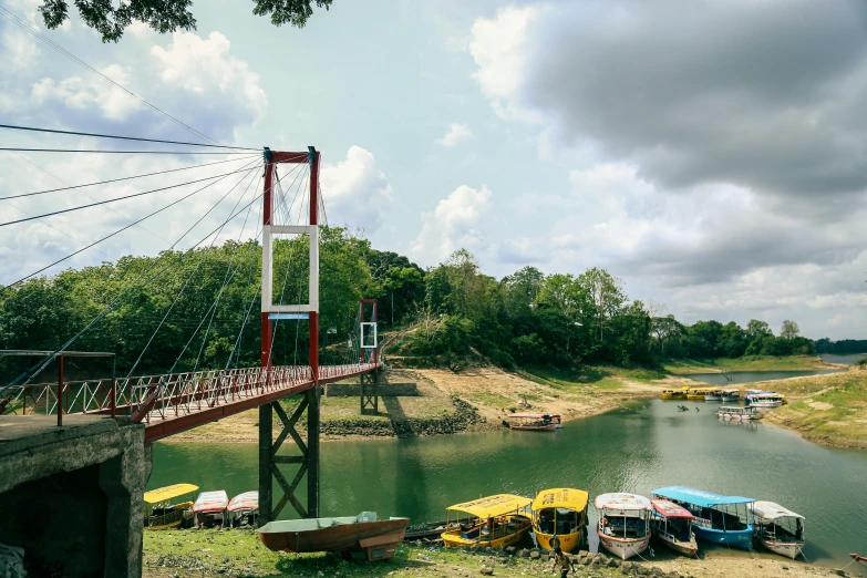 a view of some boats at the shore and people on the bridge