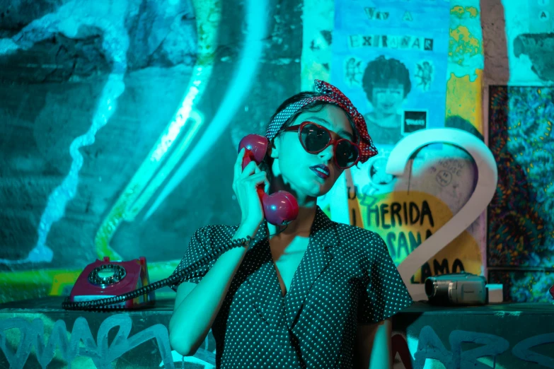 a woman talks on a cell phone in front of a wall covered with graffiti