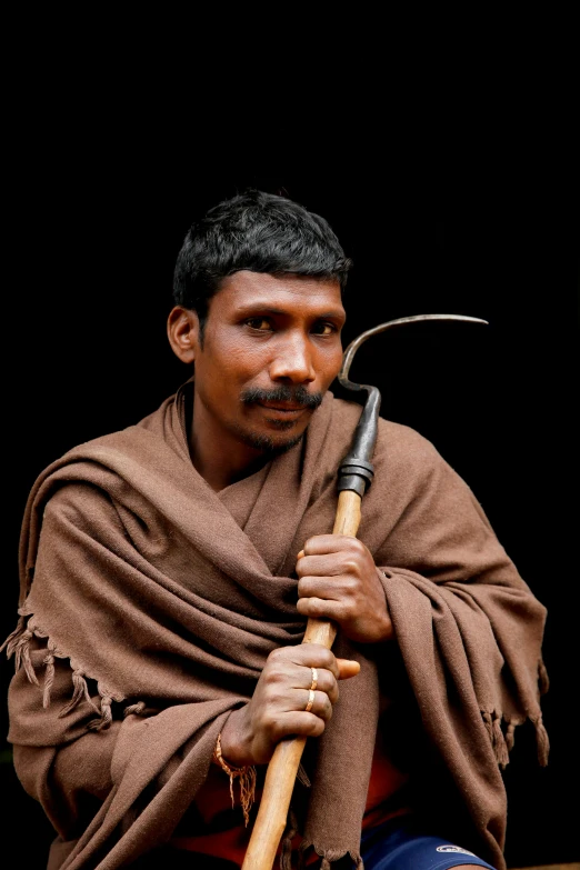 a man is holding an orange stick and wearing a blanket