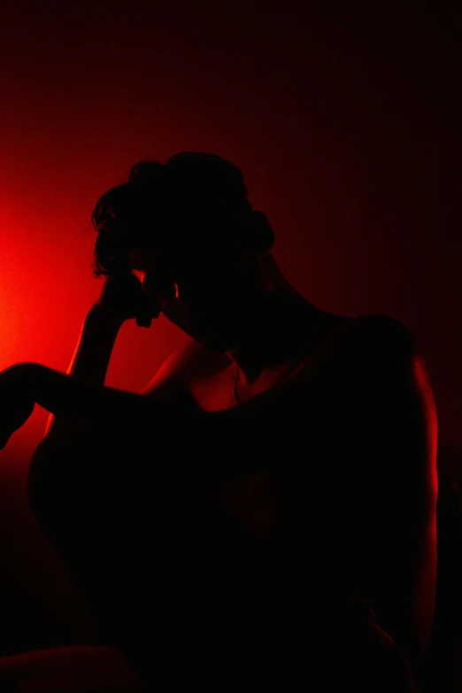 a woman sitting in the dark looking at her cell phone