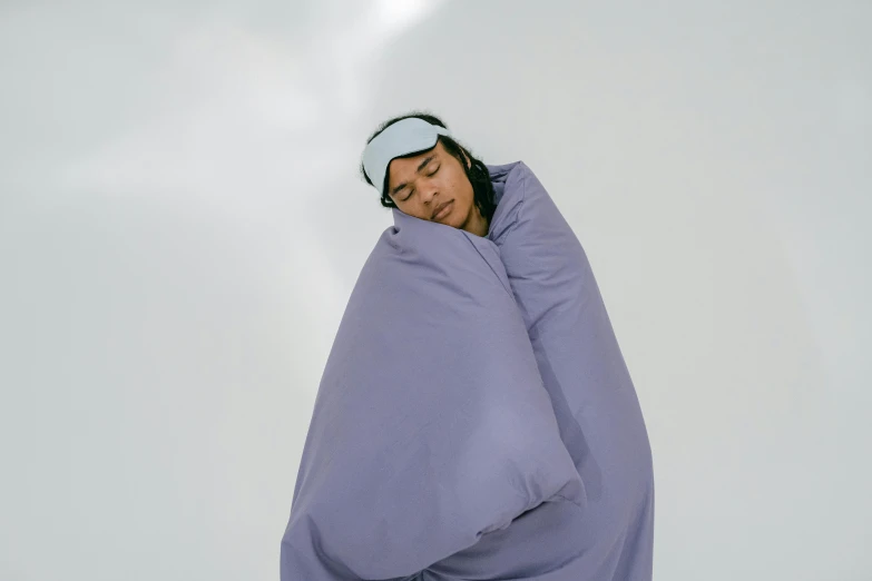 a man covering his face with a blue blanket