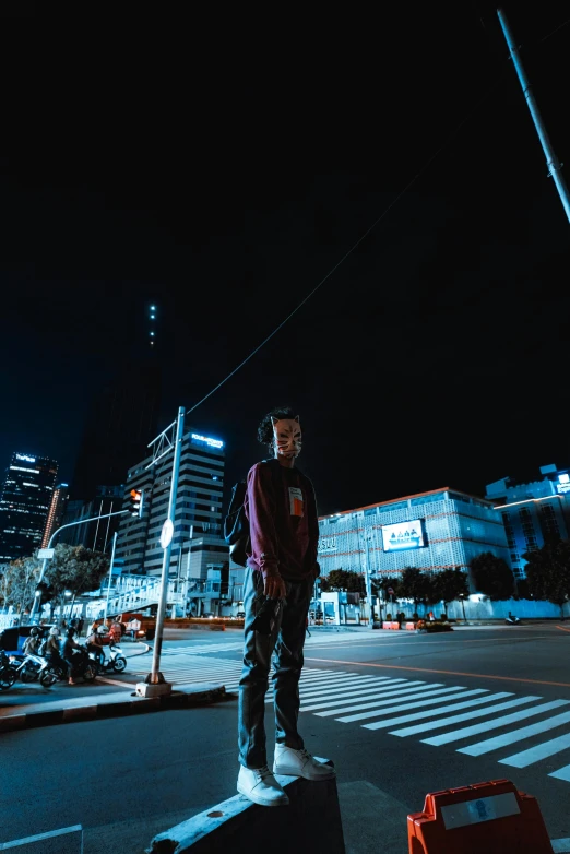 a man standing on the sidewalk in front of buildings at night