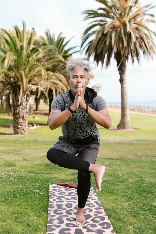 a man doing yoga in front of some palm trees