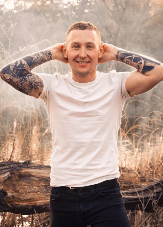 a tattooed man holding his hands behind his head